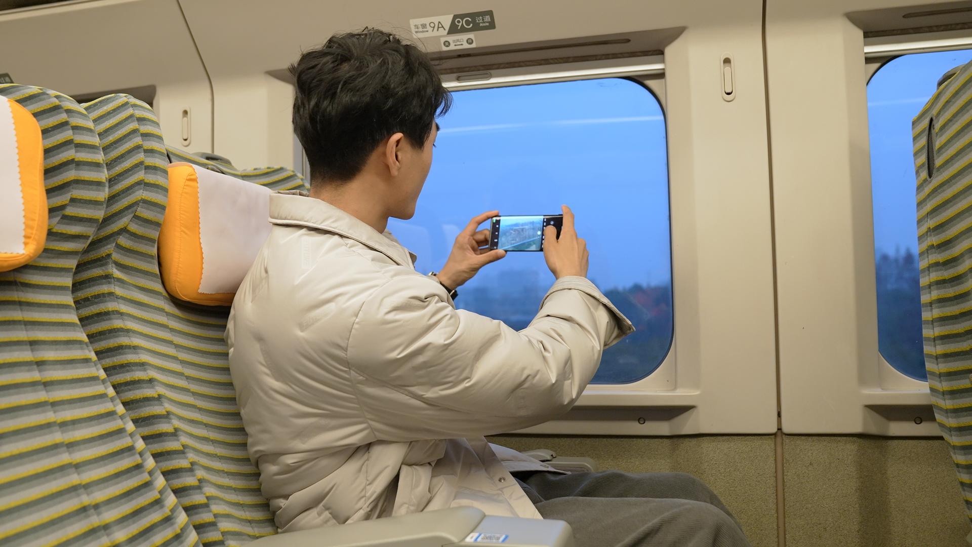 男青年乘坐高铁用手机拍窗外视频的预览图