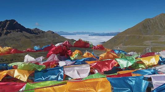 4K藏地高山垭口大风天气随风起舞的经幡以及远处的云海和雪山视频的预览图