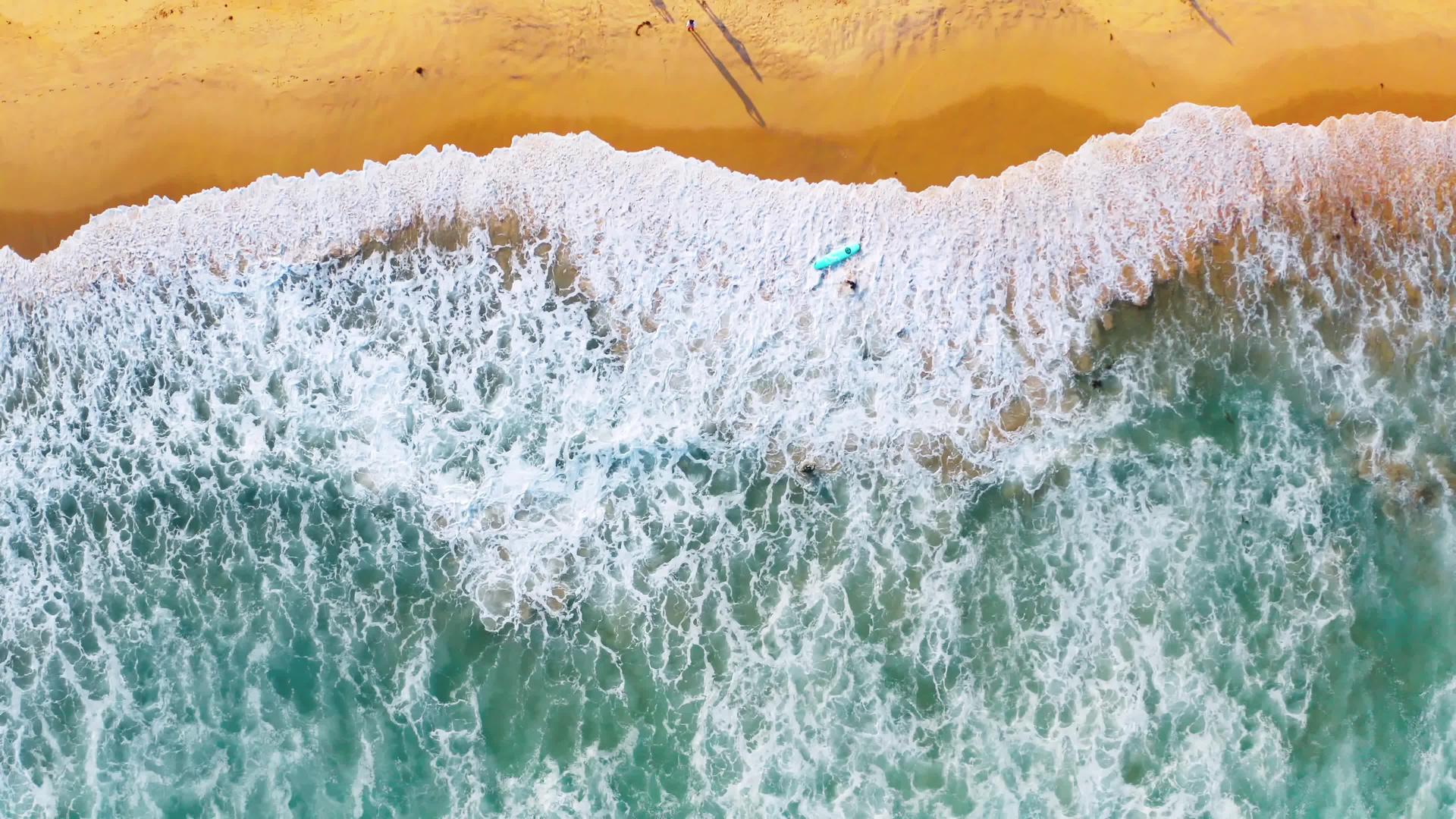 海南万宁海滩4K航拍运动员手持冲浪板视频的预览图