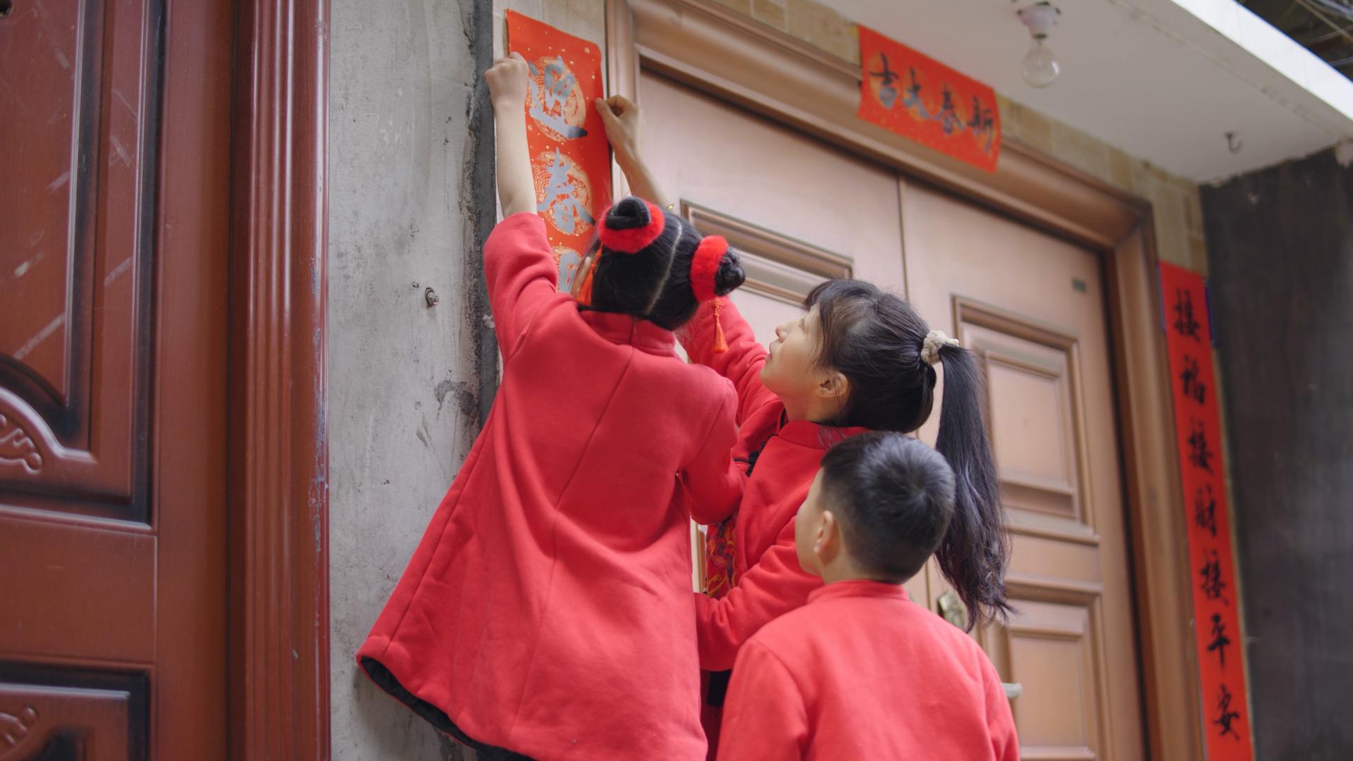 4K实拍新年春节小朋友一起门上贴对联视频的预览图