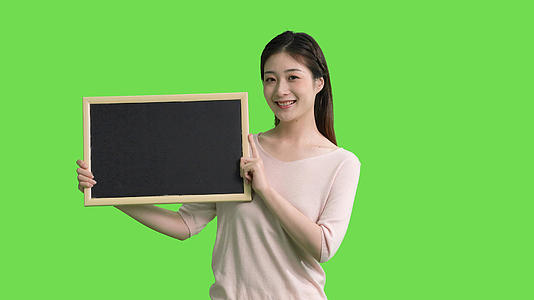 4k穿休闲服的女生手拿黑板展示动作绿幕抠像视频视频的预览图