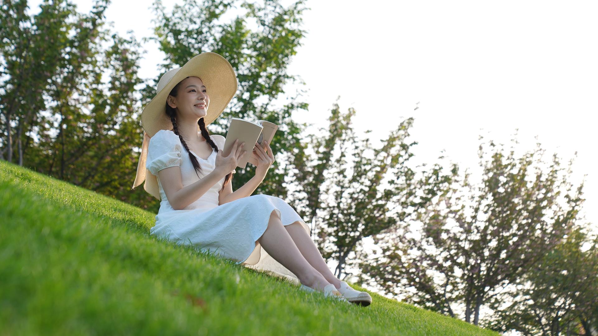 白长裙女孩在草地上看书视频的预览图