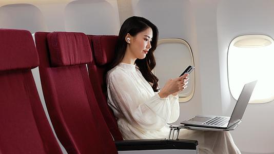 年轻美女坐在机舱座椅上浏览手机页面视频的预览图