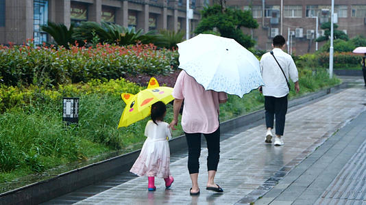 梅雨季升格雨中撑伞的母女家长接送孩子放学亲子时光母女背影视频的预览图