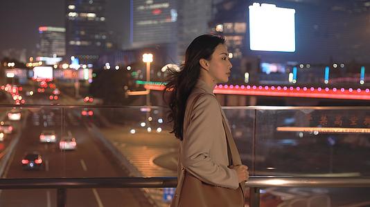 独自走在城市夜晚天桥上的年轻女性视频的预览图