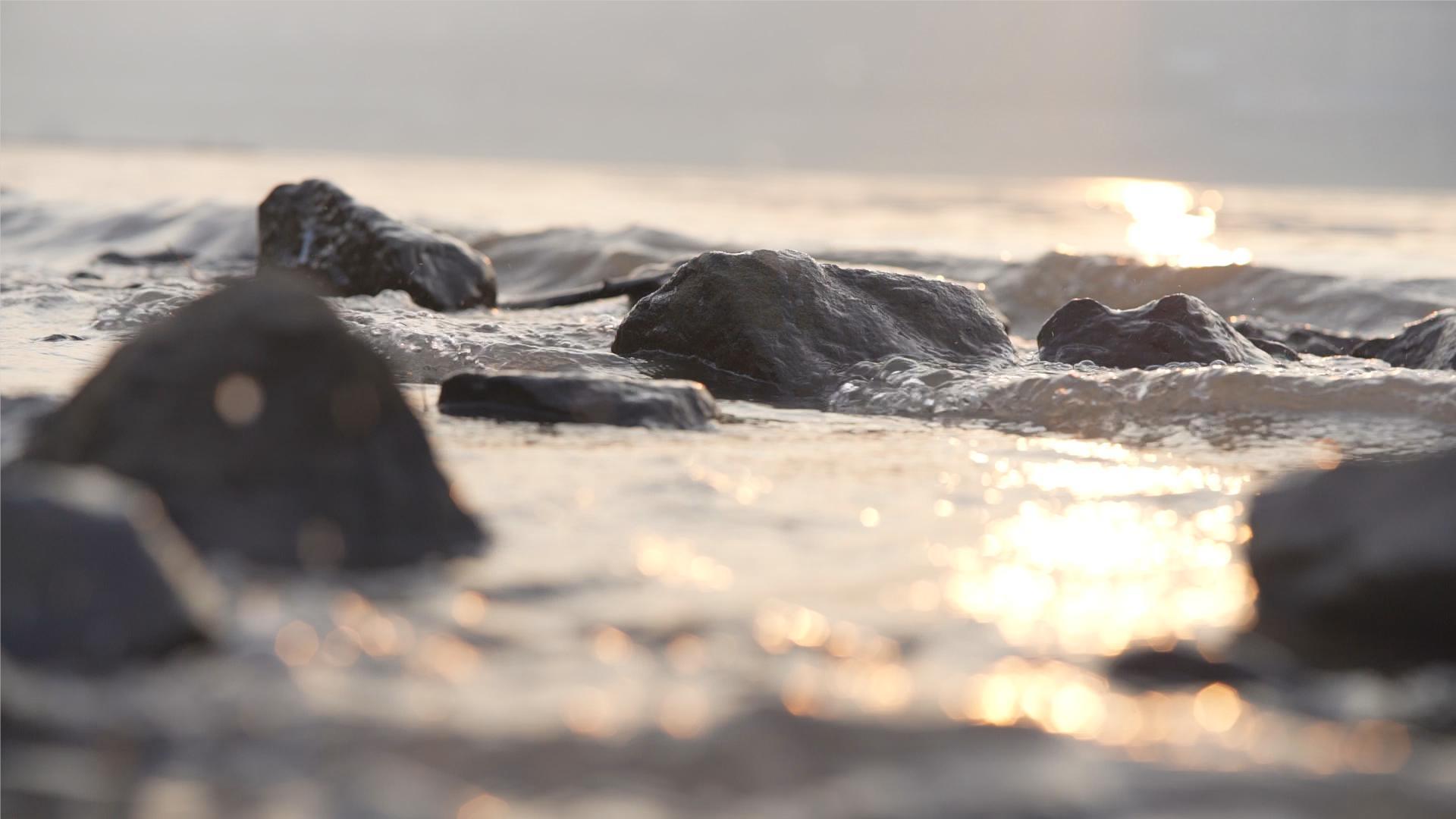 升格拍摄唯美画面夕阳浪花江边石头视频的预览图