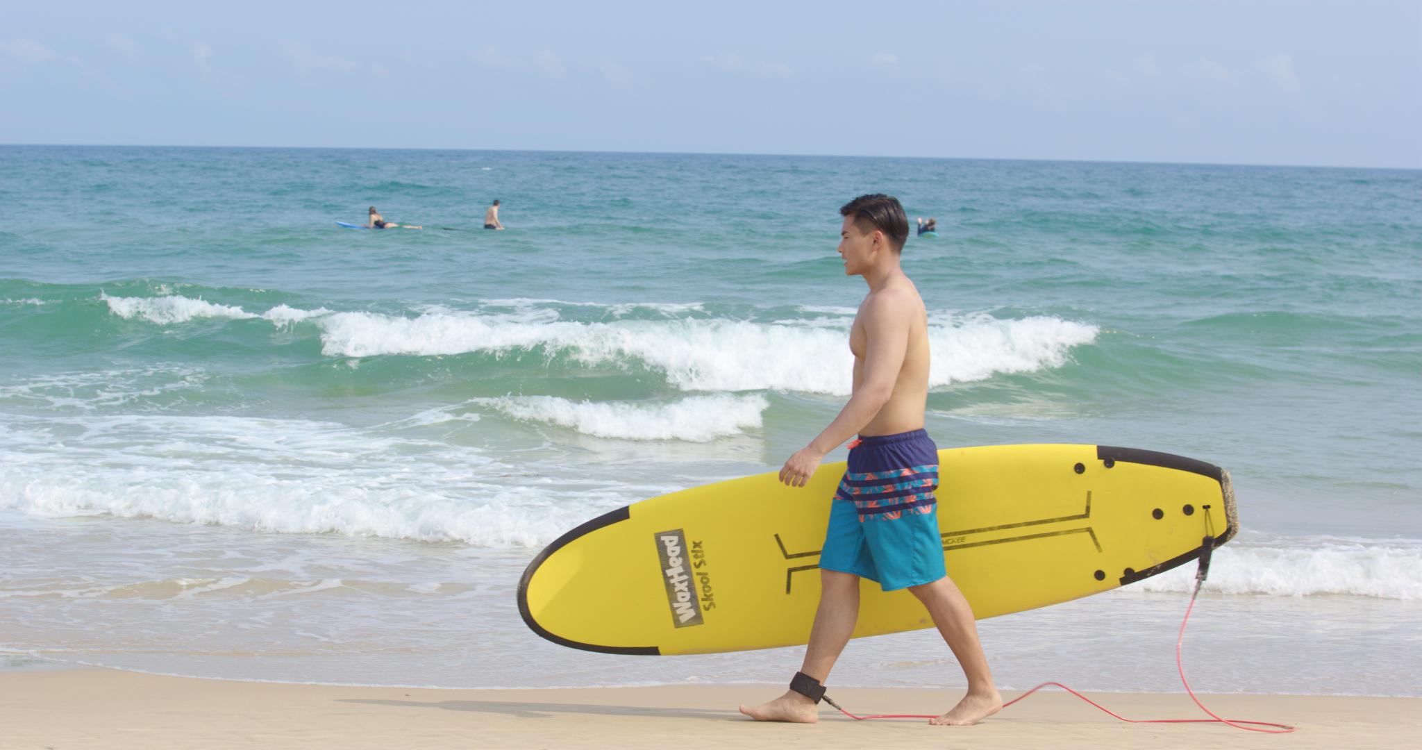 8K海边男青年抱着冲浪板走在沙滩上视频的预览图