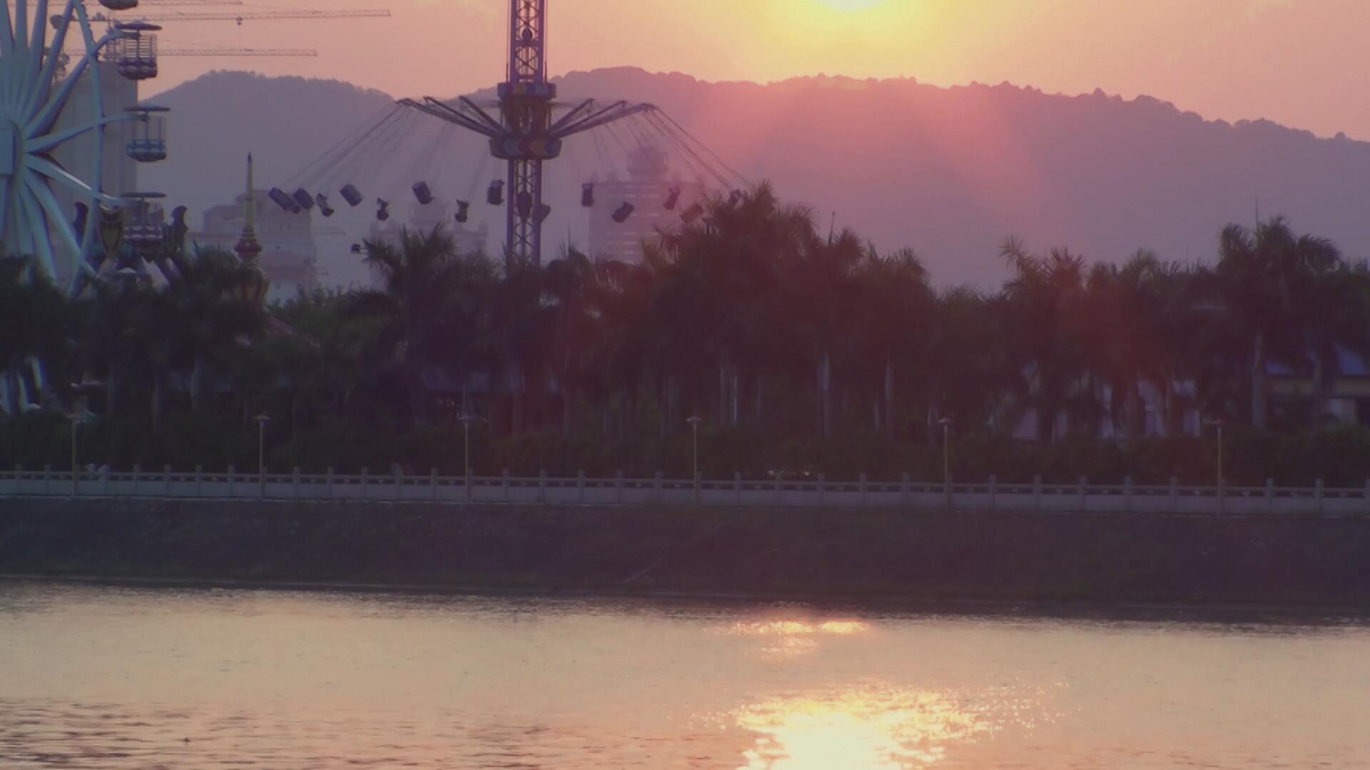 4k夕阳黄昏倒影波光粼粼的湖面游乐场视频的预览图