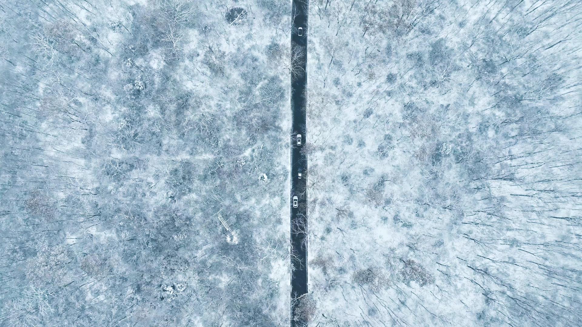 4K航拍大雪景观冬季大雪森林公路雪中行驶的车流视频的预览图
