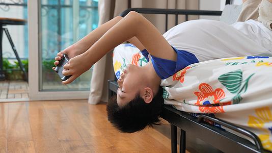 小男孩倒立在沙发上玩游戏机视频的预览图