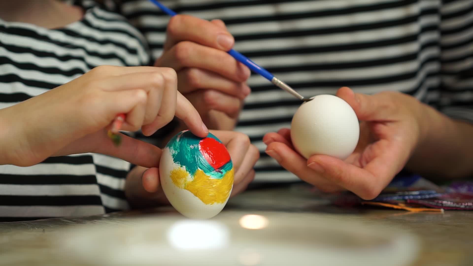 母亲和女婴用手给鸡蛋涂颜料视频的预览图