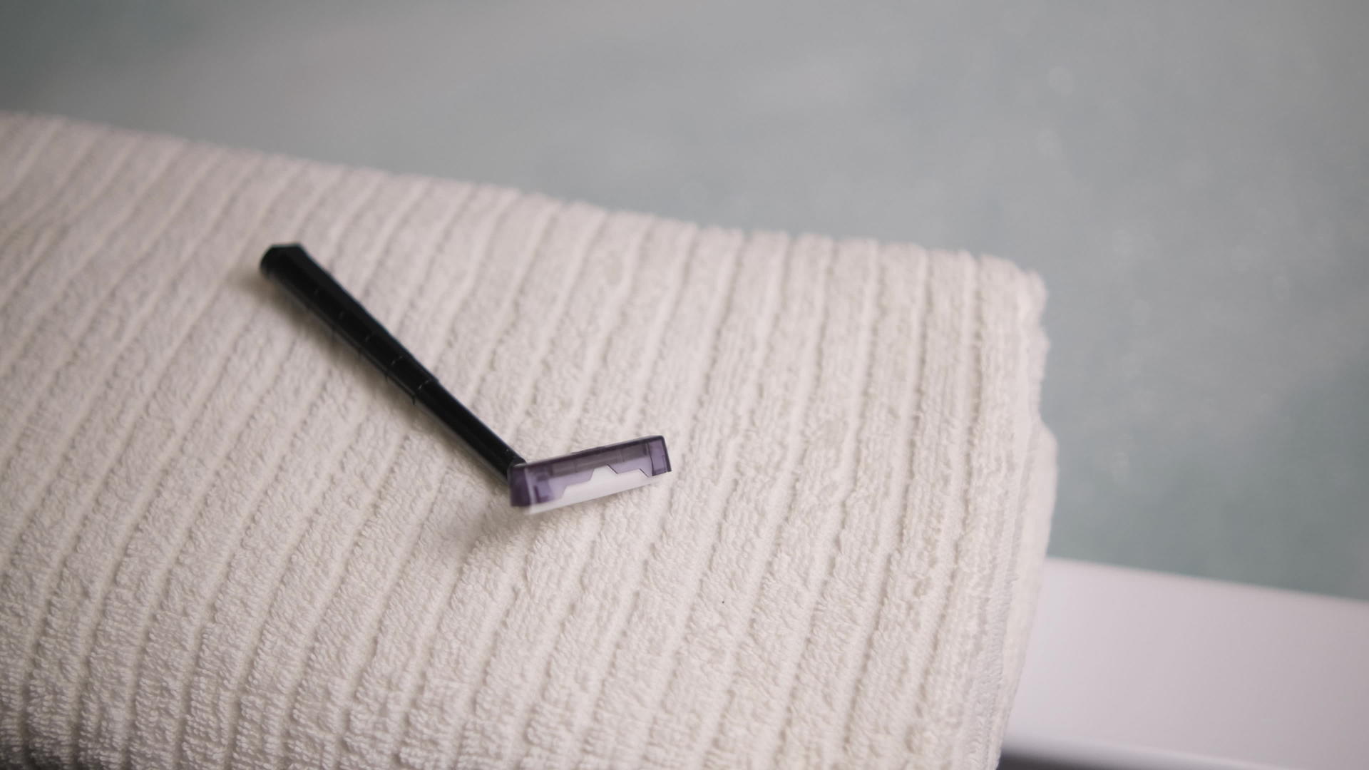 一名男子把一次性剃须刀放在浴室的毛巾上视频的预览图