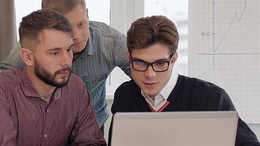 四个年轻的创意管理青年在办公室看笔记本电脑视频的预览图