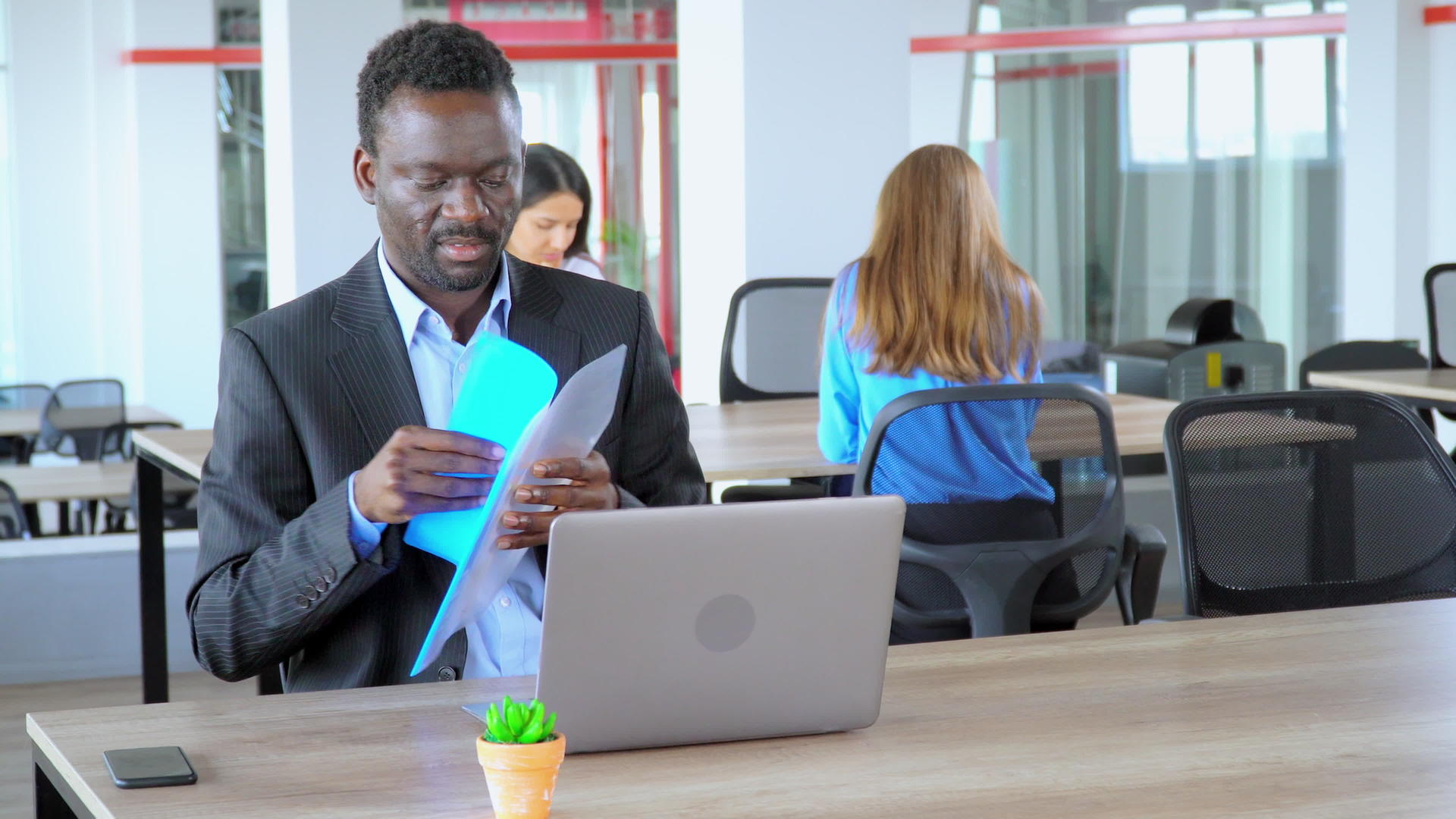 非裔美国人经理在初创公司的开放空间办公室工作持有文件夹视频的预览图