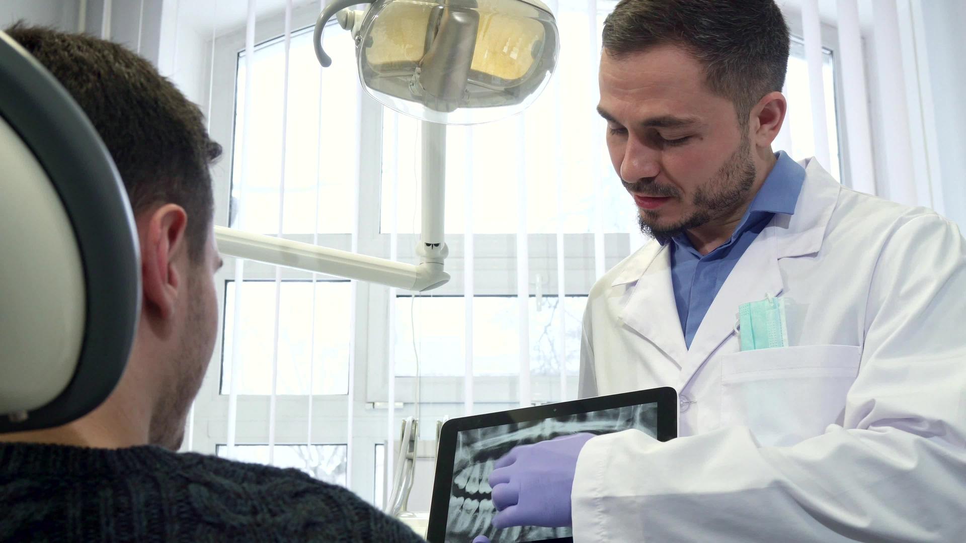 牙医在他的平板电脑上显示男性客户的X光片视频的预览图