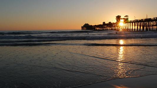 美国加利福尼亚州的日落码头剪影海滨冲浪胜地海洋热带海滩冲浪者在等待波浪视频的预览图