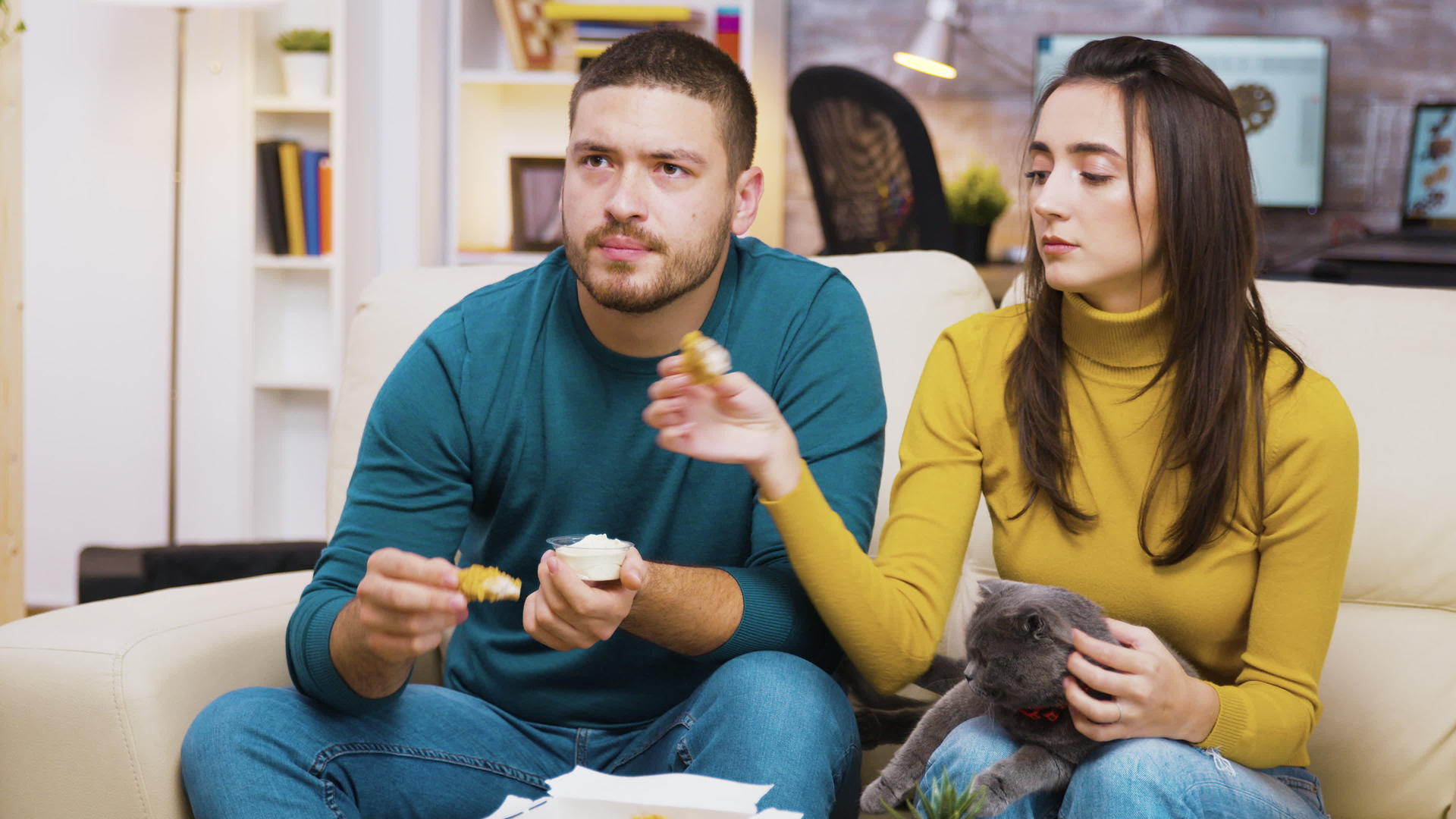 年轻夫妇坐在沙发上吃炸鸡视频的预览图
