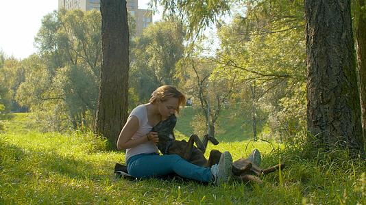 美丽的女人和她的狗在公园里视频的预览图