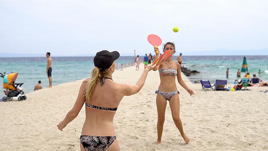 两个漂亮的年轻女孩在沙滩上打网球和拍拍视频的预览图