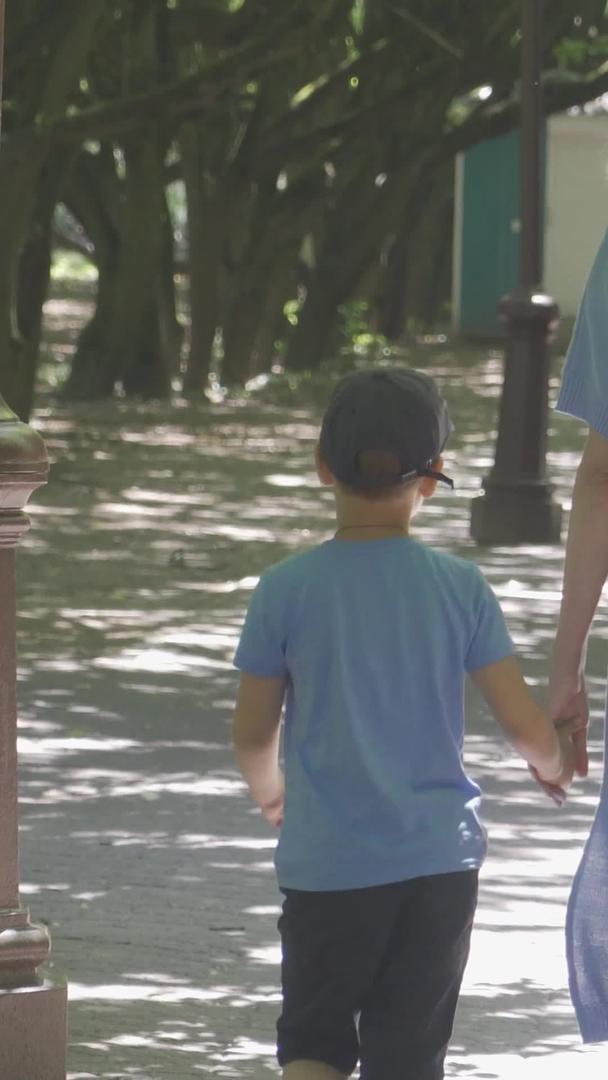 暑假儿童亲子公园林荫路下牵手漫步视频的预览图
