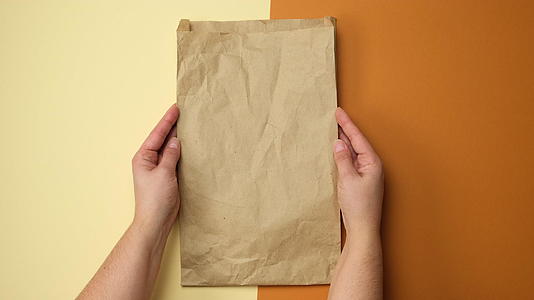 两只手拿着棕色的纸袋Kraft棕色背景的顶层风景视频的预览图