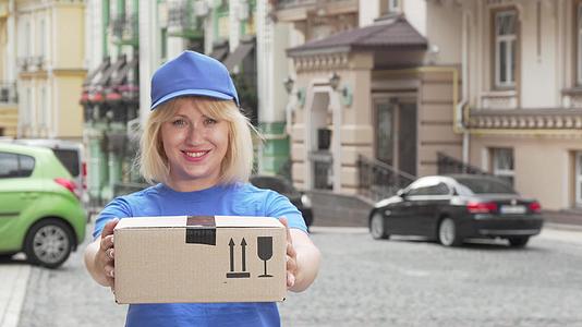 快乐的女性穿着蓝色制服手持纸板盒视频的预览图