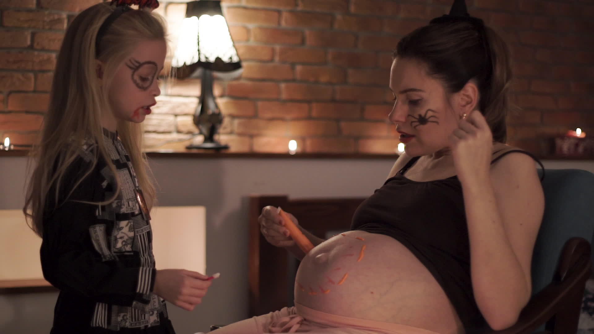 怀孕的母亲和女儿在万圣节画南瓜肚子玩得很开心视频的预览图