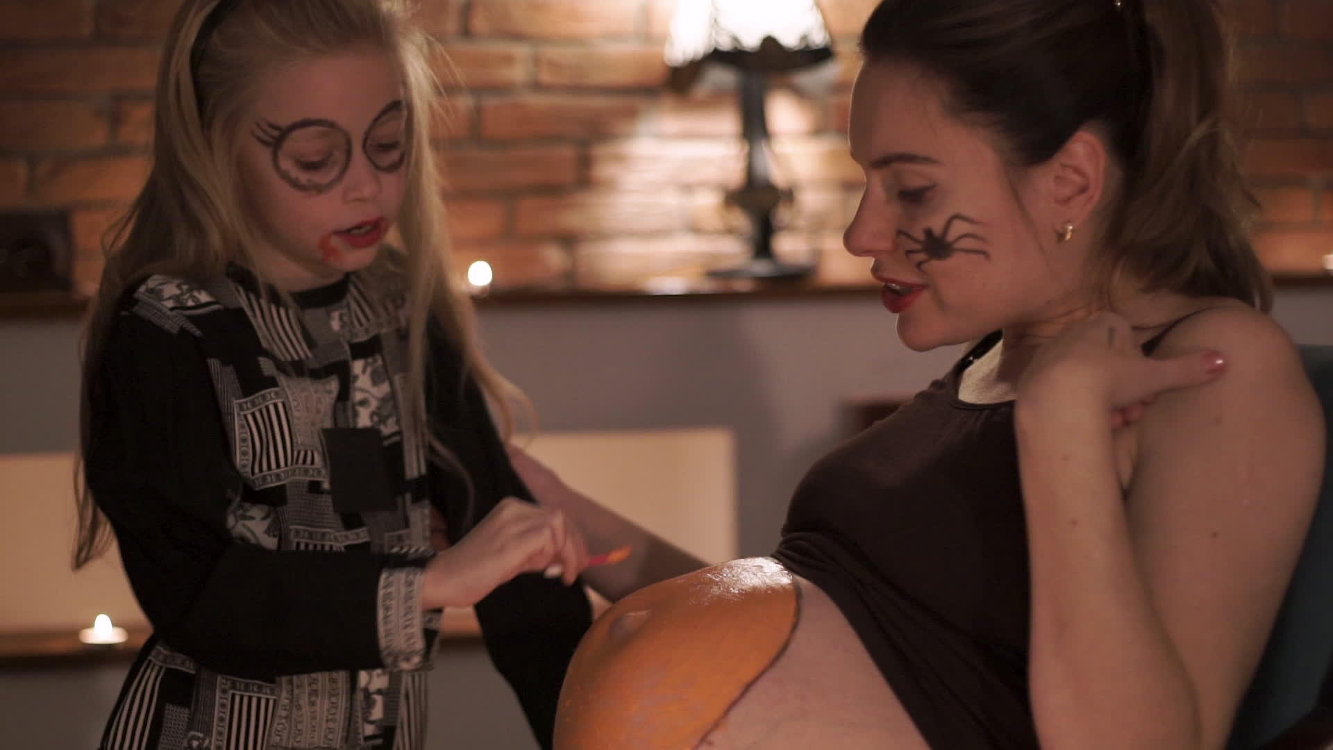 怀孕的母亲和女儿在万圣节之夜在肚子上画南瓜视频的预览图