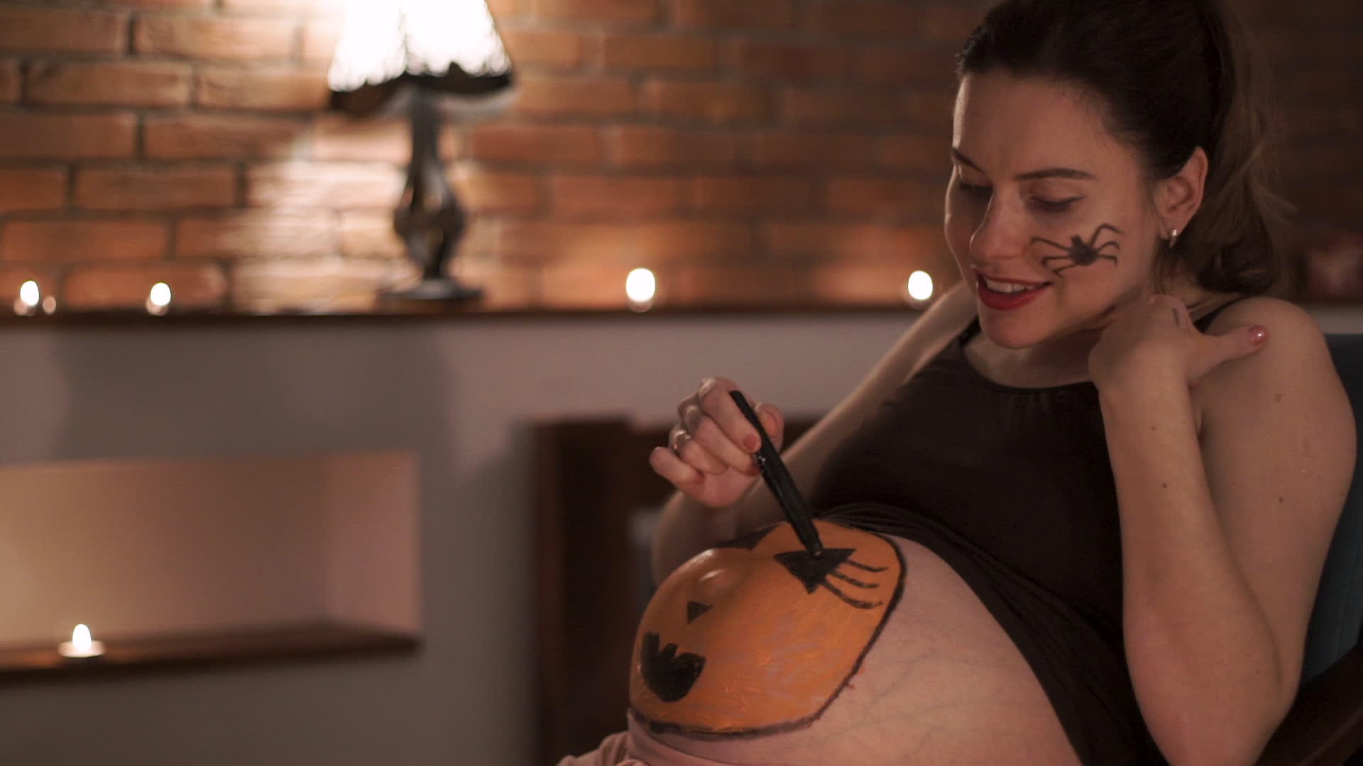 孕妇在神圣的夜晚画南瓜肚子视频的预览图