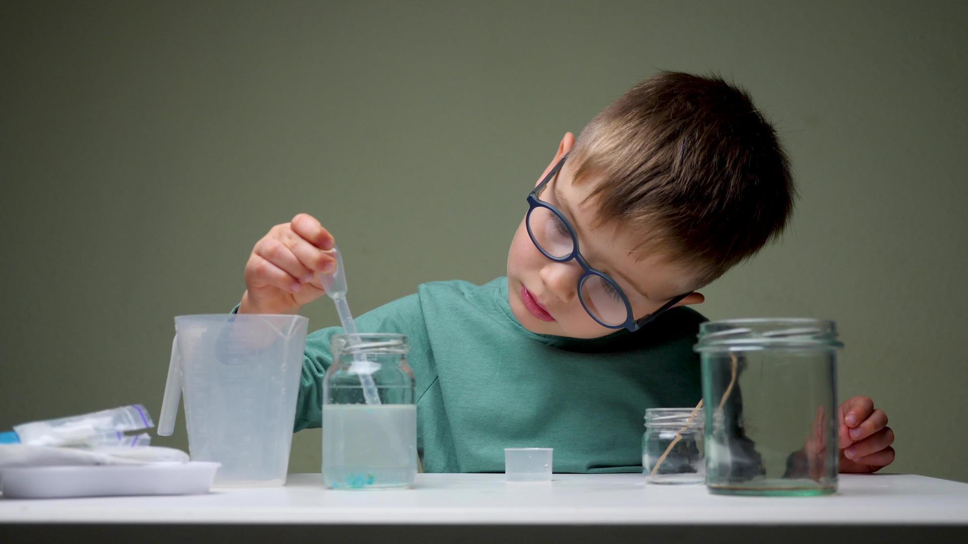这个可爱的男孩在学生桌子的化学实验室里用移液器在家里上学视频的预览图