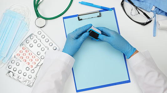一名医生在医生服务台戴着电子脉冲氧气计和蓝色乳胶手套视频的预览图