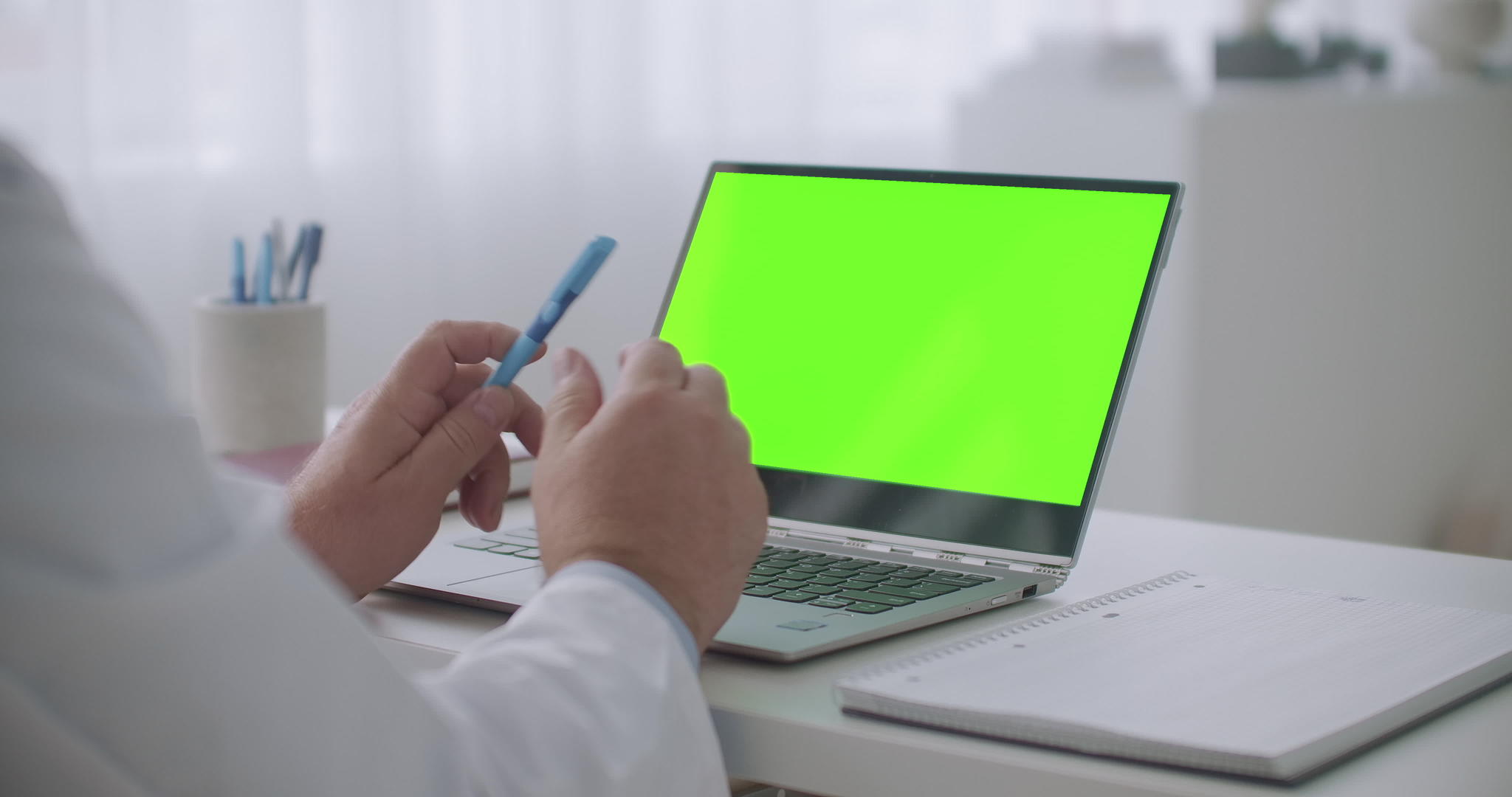 医生在在线医疗会议上讲课在笔记本电脑上用绿色屏幕对着桌子视频的预览图