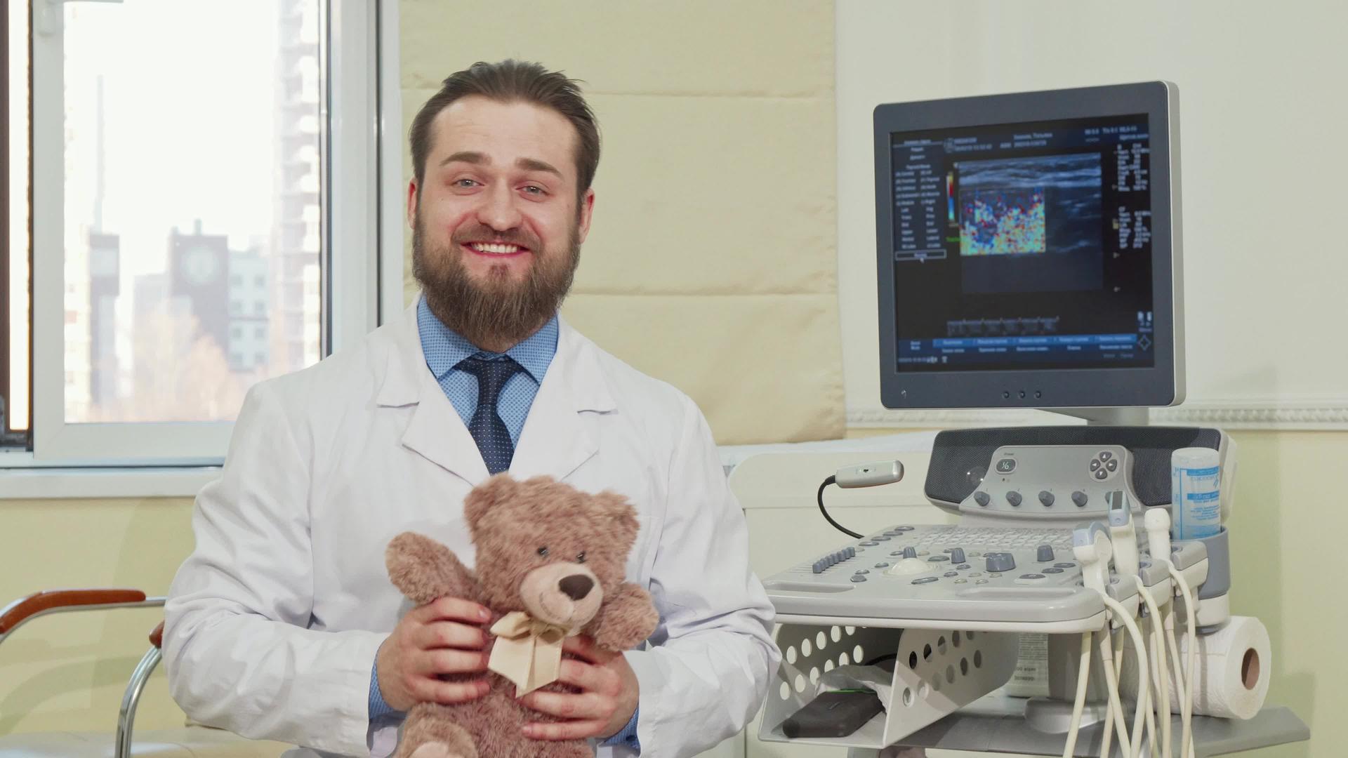一位友好的男儿科医生拿着泰迪熊玩具向相机挥手视频的预览图