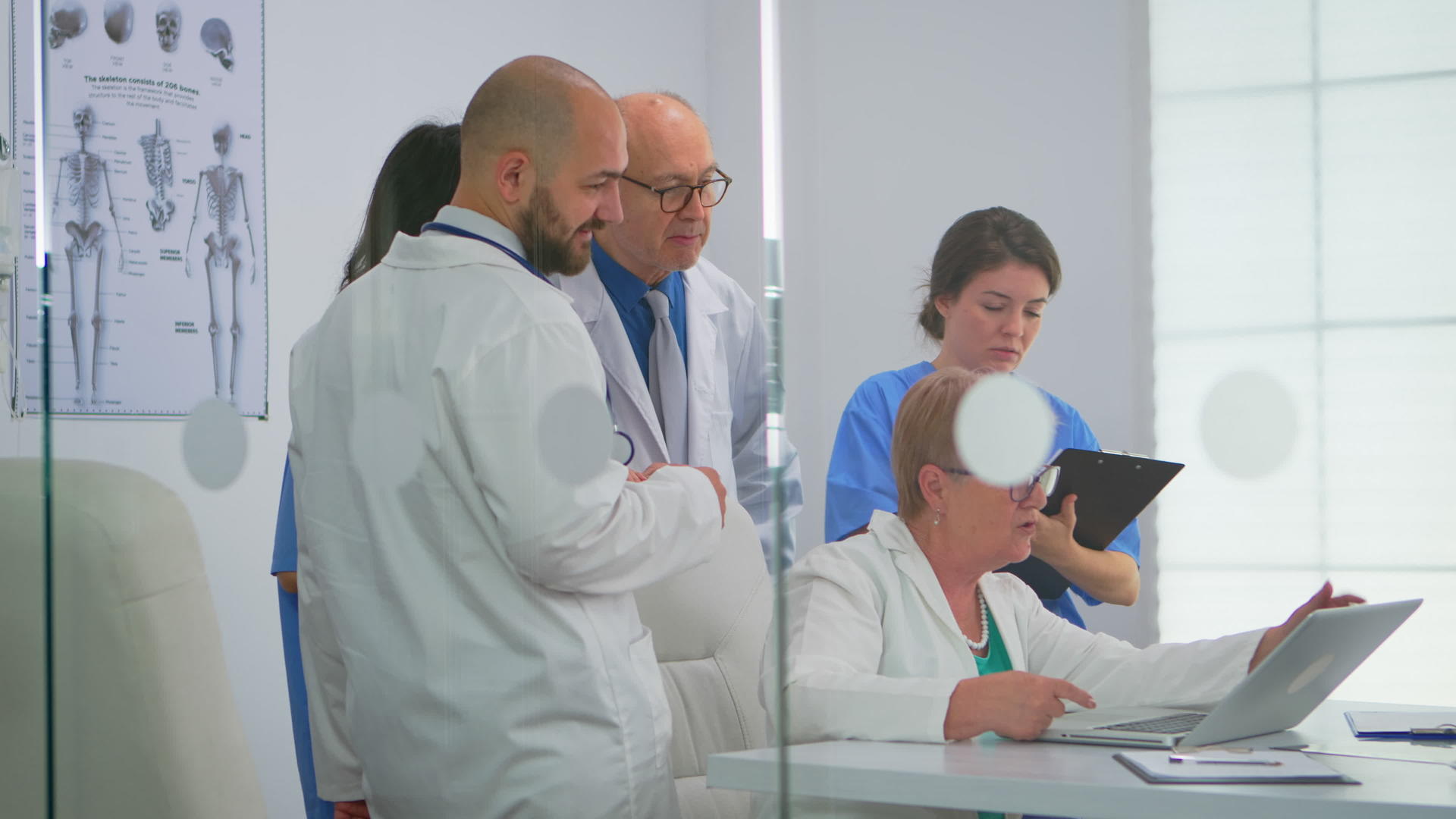 高级医生用膝上电脑向同事解释患者的治疗情况视频的预览图