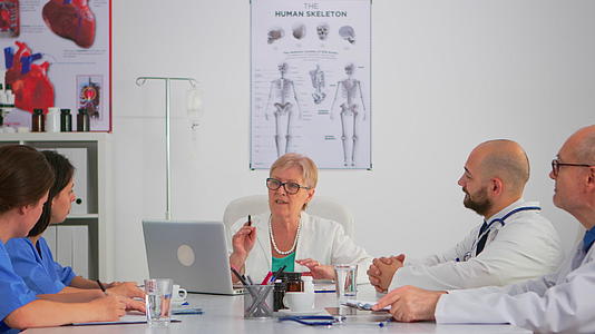 老年女专家专家坐在会议桌上与小组交谈视频的预览图