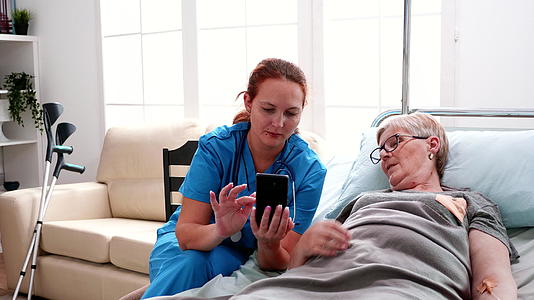 帮助老年妇女使用智能手机的女护士视频的预览图