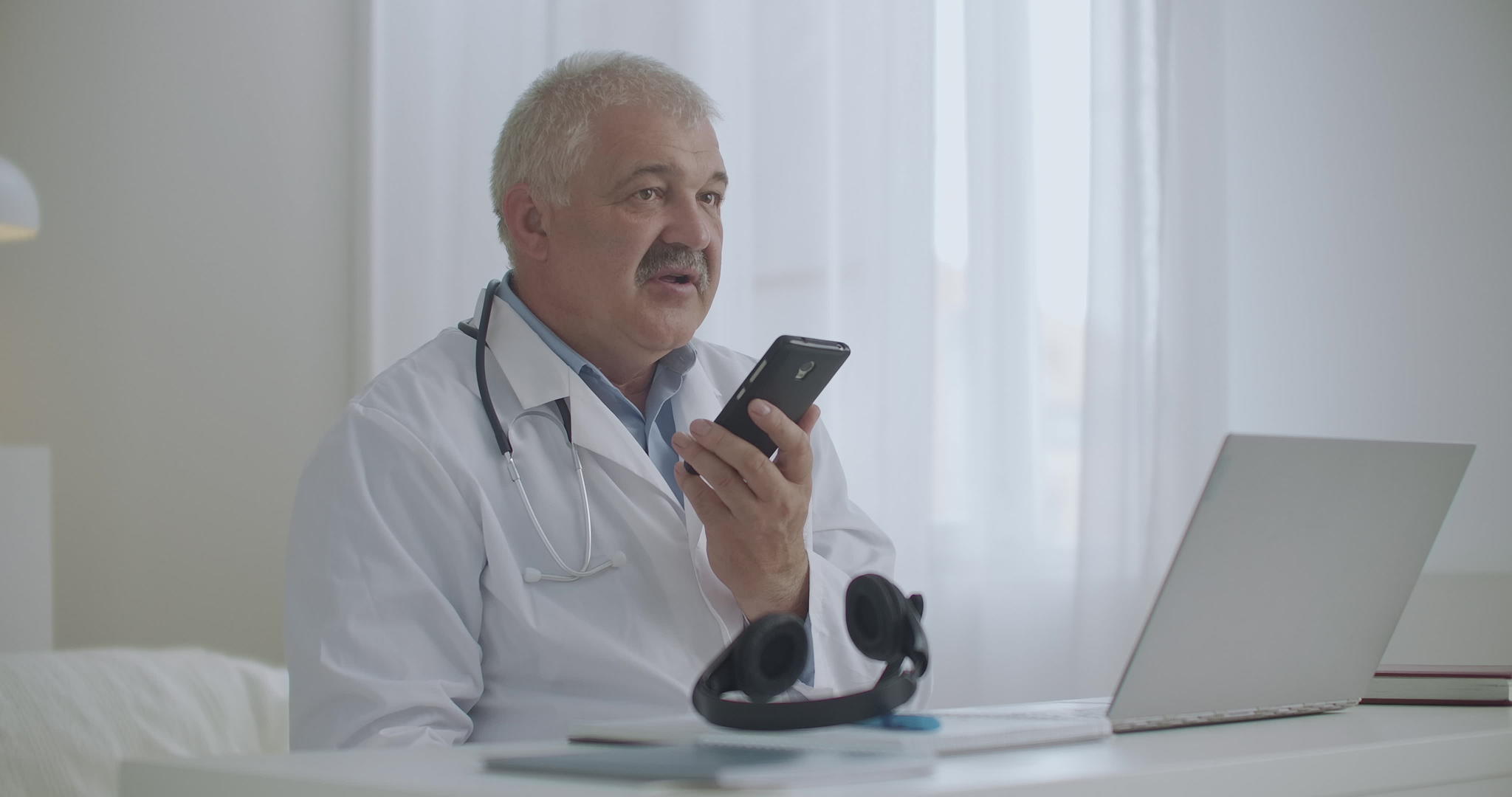 男医生在诊所办公室用免提电话交流病情视频的预览图