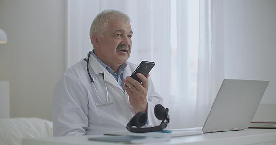 男医生在诊所办公室用免提电话交流病情视频的预览图