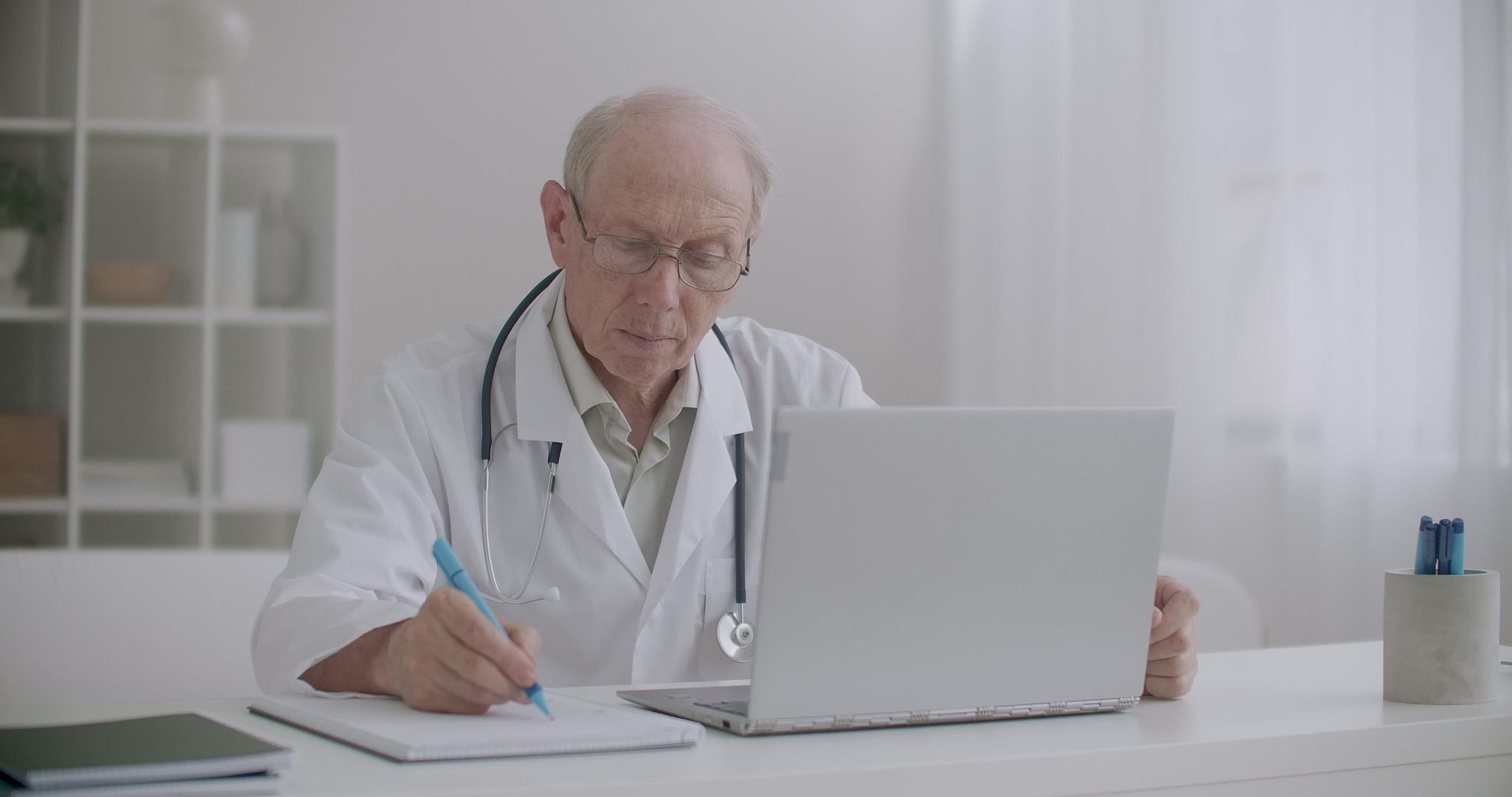 老年医生在网上看笔记本电脑屏幕视频的预览图