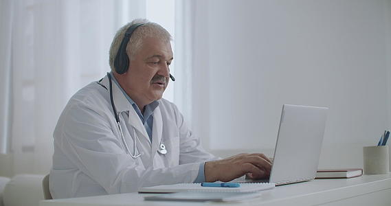 男医生正在通过笔记本电脑上的视频通话与患者在线交谈视频的预览图
