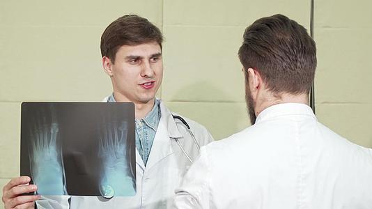 英俊的男医生和他的同事讨论了双脚X光视频的预览图