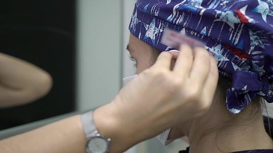 戴口罩的女医生年轻的黑发医生或者穿蓝色外套的护士视频的预览图