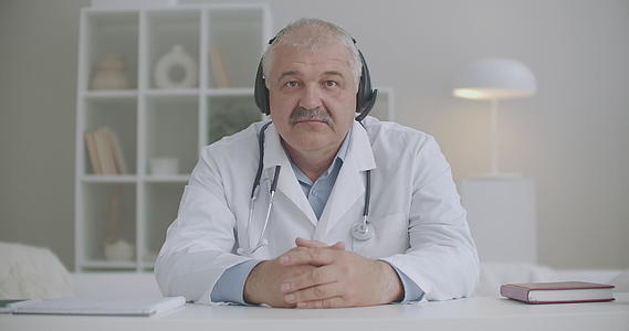 当时医生点头看着笔记本相机用耳机听病人远程医疗服务视频的预览图