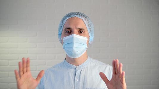 一名男医生在生病期间戴着保护性口罩用双手说话和做手势视频的预览图