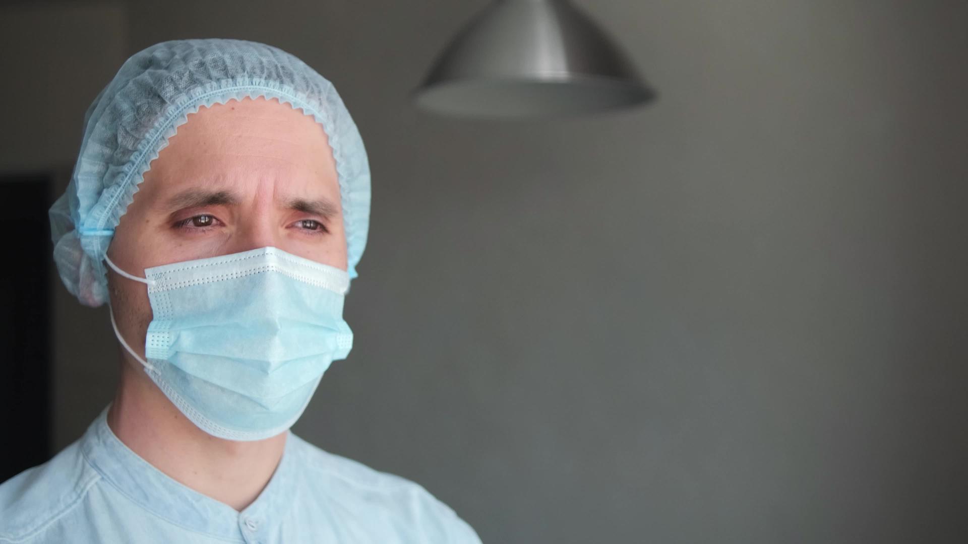 一名疲惫的男医生在生病期间戴着保护性口罩视频的预览图