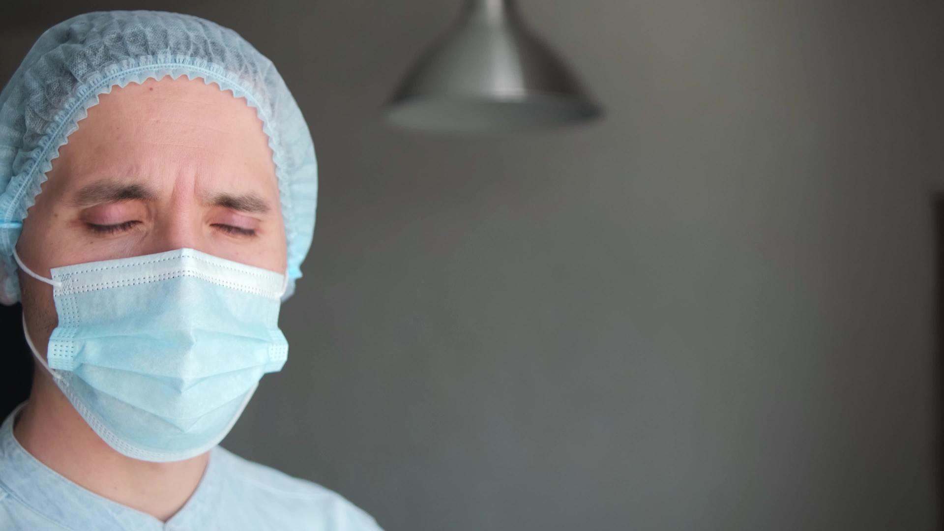 一名疲惫的男性医生在生病期间戴着保护性口罩视频的预览图