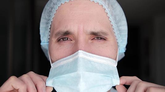 一名疲惫的男医生在生病期间戴着保护性口罩医生脱下了保护性口罩视频的预览图