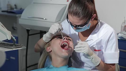牙科外科医生用牙科探牙器检查患者的牙齿视频的预览图