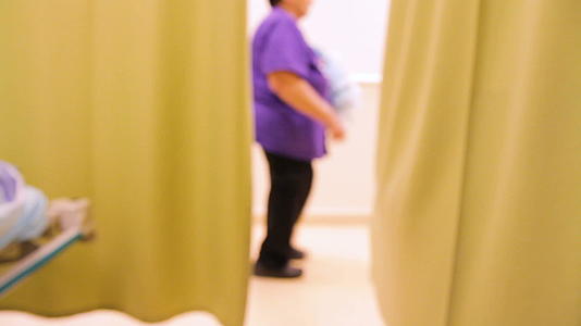 身份不明的病人和工作人员在医院走廊从一边到另一边视频的预览图