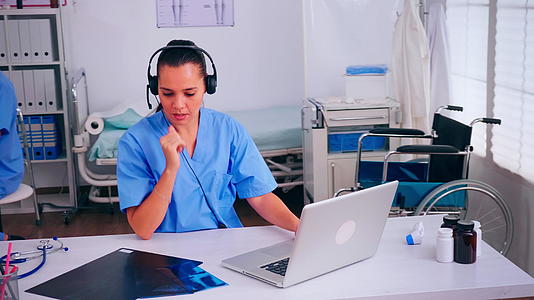 在医院使用耳机的外科医生助理在医院接听病人的电话视频的预览图